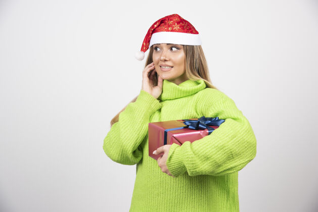 年轻一个年轻的女人拿着圣诞礼物礼品盒圣诞老人帽子