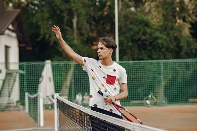 成人今天玩得很开心 穿着t恤的年轻人手里拿着网球拍和球的家伙嬉戏男性人