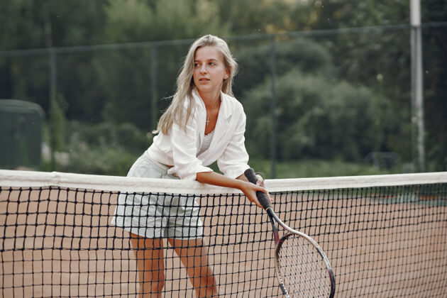 活动穿着t恤的快乐的年轻女子拿着网球拍和球的女子球拍专注运动员