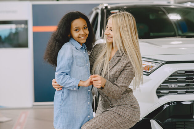 美国一家人在汽车沙龙里买车的女人和妈妈在一起的非洲小女孩车辆开朗混合