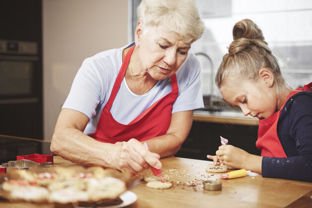 儿童奶奶和女孩一起烤饼干和装饰饼干向下妇女饼干