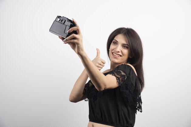 摄影师黑发女人用相机自拍看持有照片