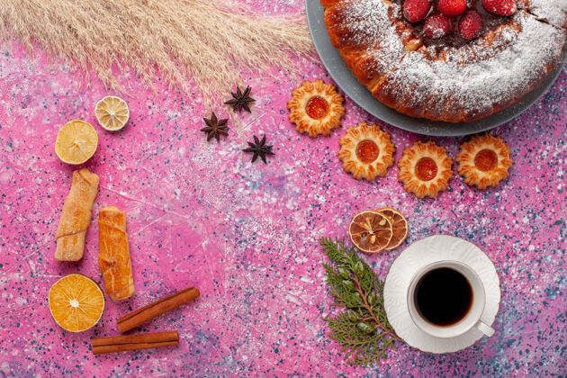 蛋糕俯瞰美味的草莓蛋糕与饼干百吉饼和一杯茶的粉红色背景蛋糕甜甜甜甜饼干派顶部生的早餐