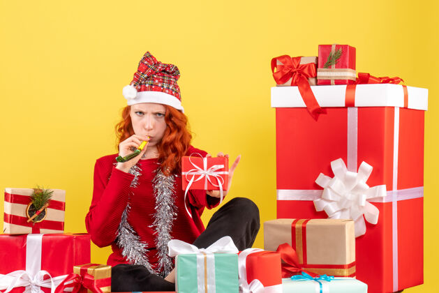 礼物年轻女子围坐在黄色墙壁上的不同圣诞礼物前视图不同帽子盒子