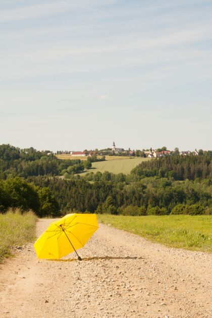 农场一把开着的黄色雨伞在乡间公路上的垂直镜头垂直草云