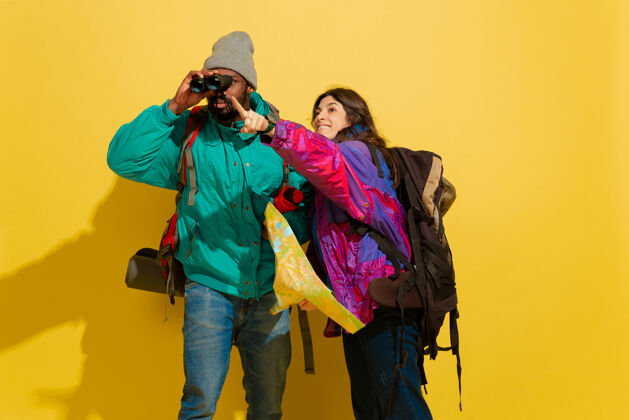 饱满一对快乐的年轻旅游情侣被隔离在黄色的画像明亮衣服长度