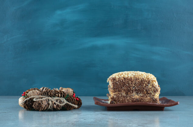 花圈松果花环旁边的一个盘子与蛋糕片大理石表面可口切片圣诞节