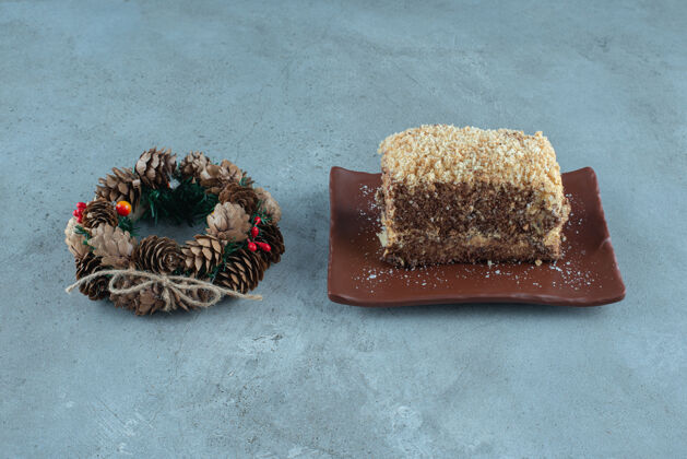 蛋糕松果花环旁边的一个盘子与蛋糕片大理石表面切片松树开胃