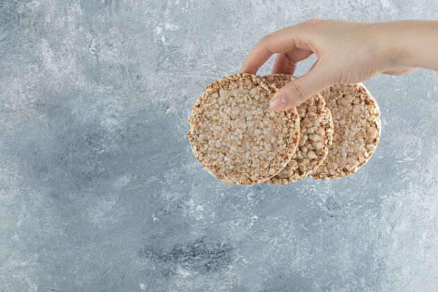 膨化的女人的手拿着酥脆的面包放在大理石表面食物脆的零食