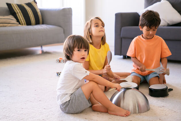 高兴快乐的孩子们坐在地毯上玩餐具可爱的白人小男孩和金发女孩在客厅里一起玩 敲盘子童年和家庭活动的概念小金发白人
