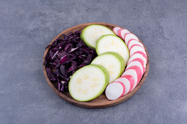 极简把西葫芦片 紫白菜和粉红萝卜放在木盘上健康沙拉素食