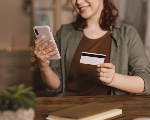 水平笑脸女人在家用智能手机刷卡信用卡小工具人