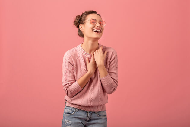 女士穿着粉色毛衣 戴着墨镜 在粉色工作室的背景下 一个年轻漂亮的开怀大笑的女人表情微笑年轻