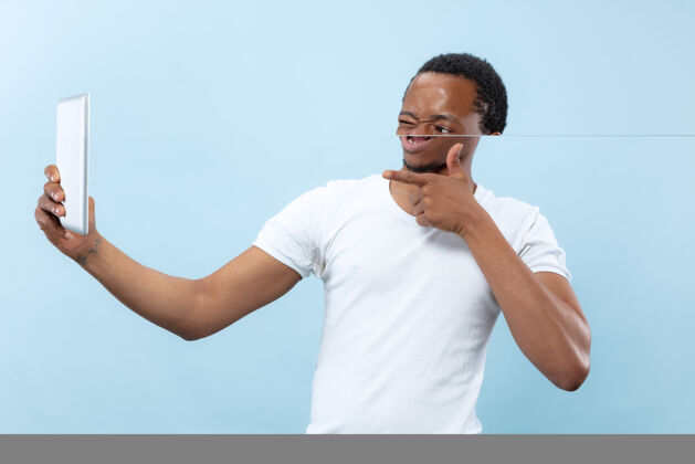 男人身穿白衬衫的非洲裔美国年轻人的特写肖像使用平板电脑进行自拍 视频录像机 聊天虚拟博客视图人