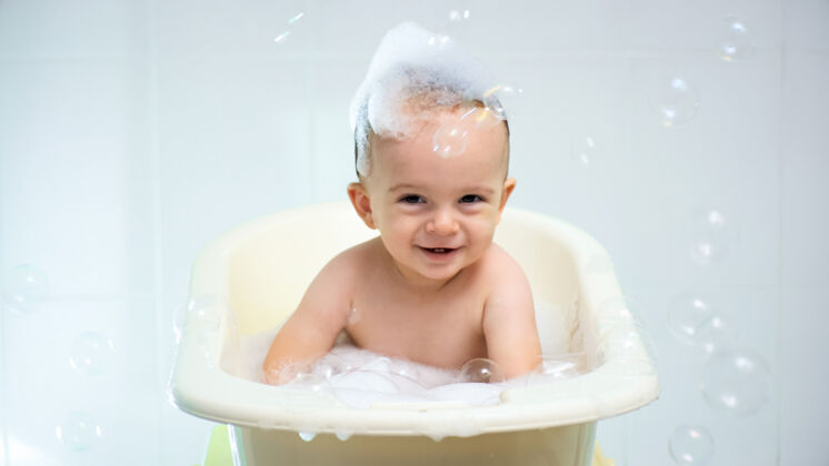 水沐浴时头上带着肥皂泡沫和洗发水的快乐微笑的小男孩的画像女人小家庭