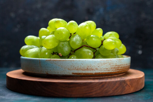 葡萄正面近距离观看新鲜的绿色葡萄 醇厚多汁的水果放在深蓝色的桌子上新鲜葡萄浆果