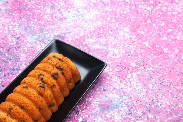 甜点正面图美味的烤蛋糕在粉红色背景的黑色蛋糕锅里香草烘焙粉色