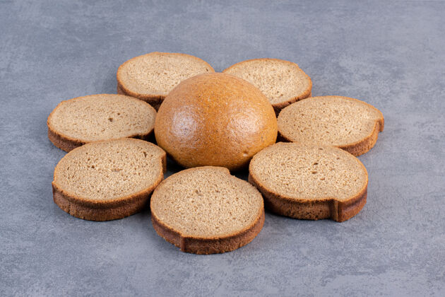 烘焙食品一圈棕色的面包片围绕在大理石上的一个小面包上饮食面粉烘焙