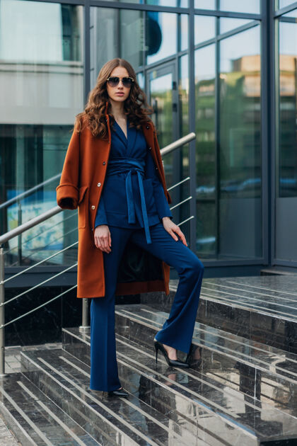 外套靓丽时尚的女人带着走在都市商业街上的暖棕色外套和蓝色西装 春秋时尚的街头风 戴着墨镜魅力时尚休闲