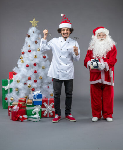 男性圣诞老人和男厨师在灰色墙上围着圣诞礼物的正视图圣诞老人圣诞快乐快乐