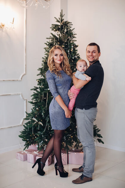 年一个快乐的年轻家庭的新的一年概念照片 一对父母和一个婴儿在圣诞树附近摆姿势圣诞快乐装饰生活方式