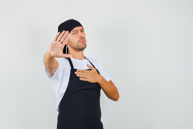 生意面包师身穿t恤 围裙 手放在胸前 显示停止的手势 看起来很无聊烹饪职业烘焙