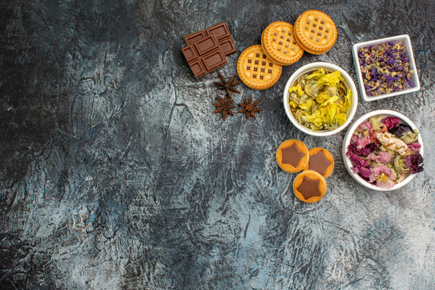 花三碗干花的顶视图 灰色背景上有巧克力和饼干灰色香料食物