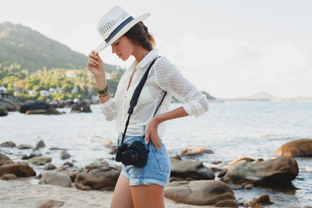 女性在亚洲度暑假的年轻漂亮的时髦女人 在热带海滩上放松 数码相机 随意的波西米亚风格 海洋风景 苗条的棕褐色身体 独自旅行旅游年轻时尚