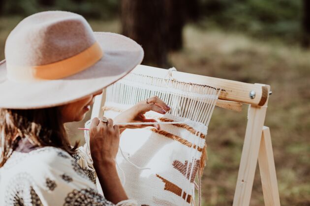 庭院一个戴着帽子 在后院的织布机上织着垫子的女人棉花文化地毯