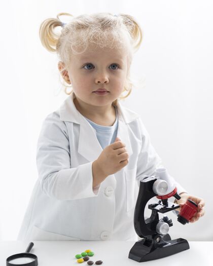 实验可爱的幼儿与实验外套和显微镜前视图放大显微镜科学