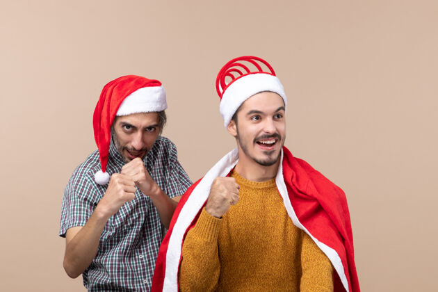 圣诞节前视图两个圣诞节的家伙 一个在打拳击 另一个在米色孤立的背景winnig手势米色风景男人