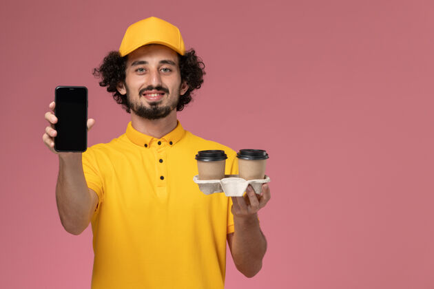 电话正面图：身穿黄色制服 披风的男性信使手拿棕色咖啡杯 粉色墙上挂着电话男制服咖啡