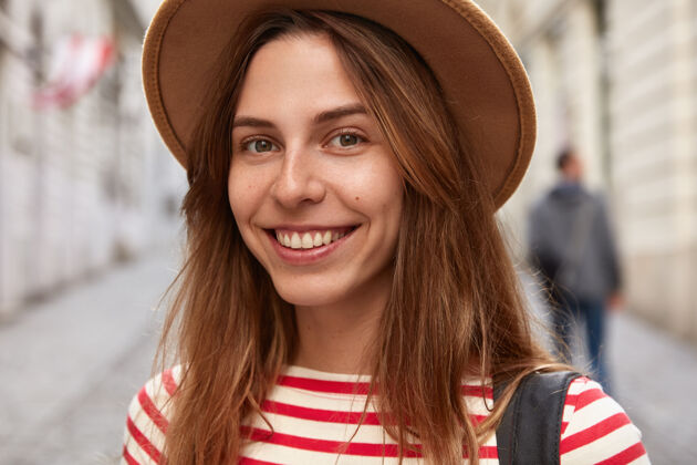 积极开朗的女冒险家戴着头饰 条纹套头衫的特写镜头 有着欢快的表情 在镇上户外漫步促销空间跳线步行欧洲