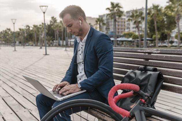 骑一个男人在外面的自行车旁用笔记本电脑工作人休息年轻