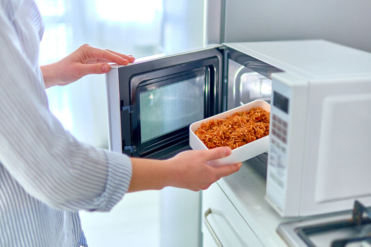 厨房女性用手在现代化的微波炉里加热一容器食物 在家吃午餐女器具晚餐