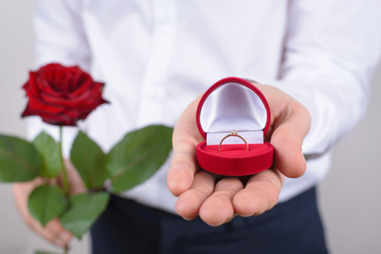 提供求婚的概念裁剪特写的开放与美丽的金环大石头隔离灰墙戒指浪漫正式服装