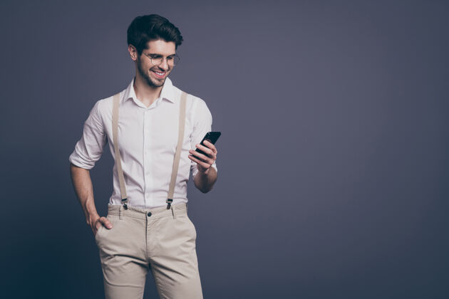 男人成功商人的肖像好心情握着电话手读工作邮件穿着正式的衣服衬衫吊带裤规格手机男性自由职业者