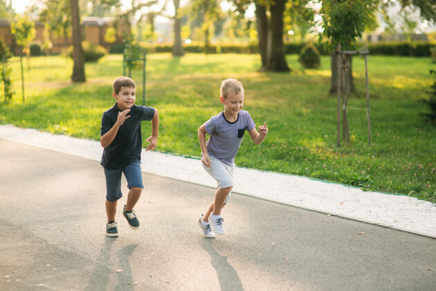活跃两个孩子在公园里玩两个穿着t恤和短裤的漂亮男孩笑得很开心二健康公园