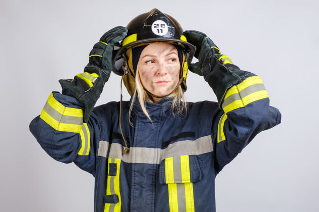 人脸穿消防员制服的年轻勇敢的女人把安全帽戴在头上女性紧急情况救援
