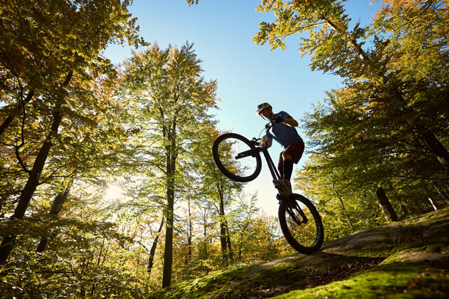 山在日落时分 职业自行车手在试骑自行车上保持平衡岩石树杂技