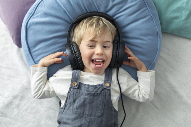 笑脸顶视图男孩用耳机听音乐科技模特年轻人