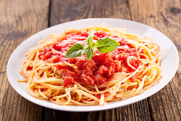素食在木桌上放一盘番茄酱和绿罗勒意大利面一餐盘子餐厅