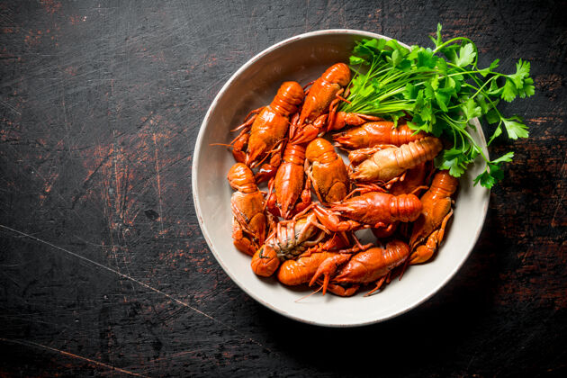 红色乡村餐桌上放着一碗煮小龙虾和欧芹小龙虾熟食河流