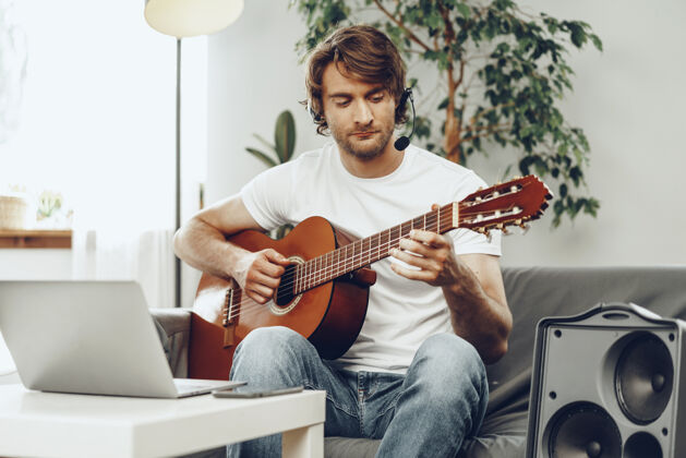 实践年轻人在笔记本上看吉他教程乐器男人公寓