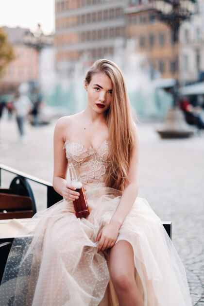 石头城弗罗茨瓦夫老城 一位穿着婚纱 留着长发 拿着酒瓶的新娘在一个古老的波兰中心拍摄婚纱照弗罗茨瓦夫市 波兰华丽时尚运动
