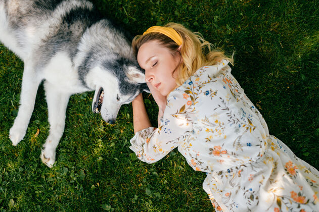 谎言一个年轻浪漫的女人和一条狗躺在草地上睡眠年轻姿势
