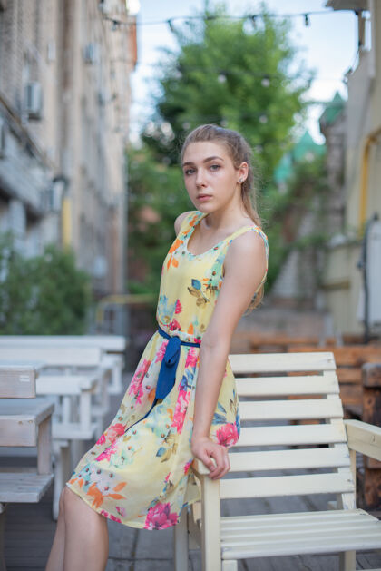 年轻一个穿着裙子的少女坐在街上的露台上金发女人公园