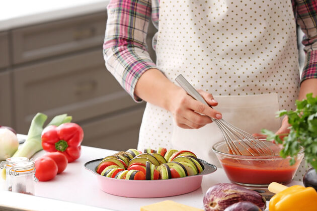 背景女人在厨房里用番茄酱拌新鲜蔬菜女人连衣裙茄子