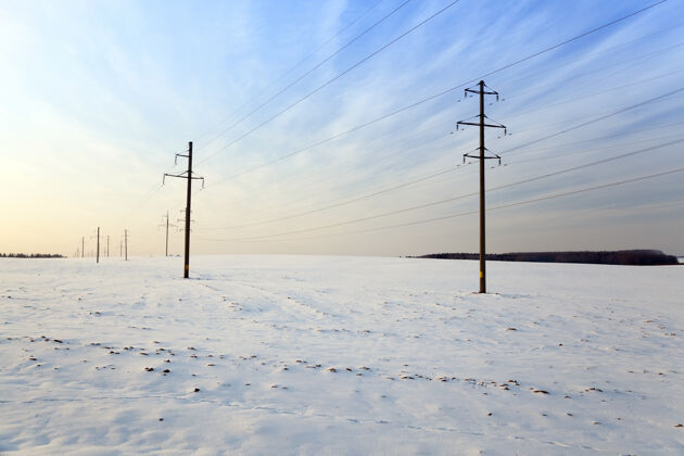 寒冷冬天被雪覆盖的田野在可见的电线杆上日落黄昏日落天空