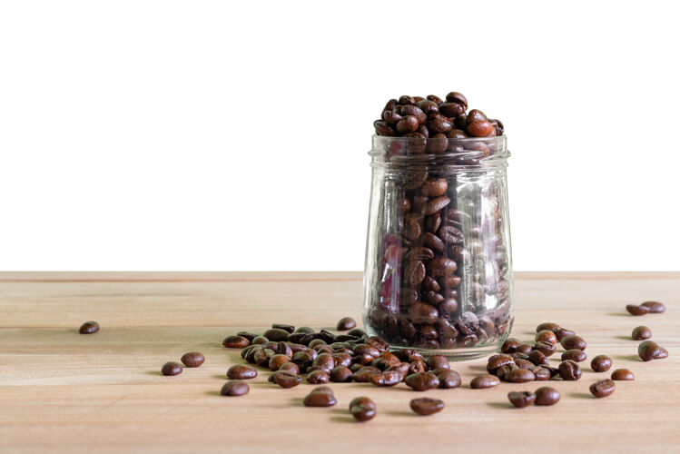 健康把烤好的咖啡豆放在玻璃瓶里 放在桌子的独立背景上木材饮食质地